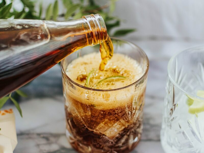 clear drinking glass with ice and brown liquid